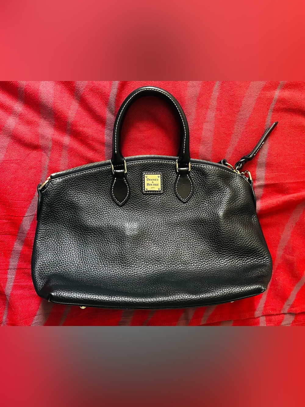 Dooney & Bourke satchel accented with polished gold-tone metal feet.